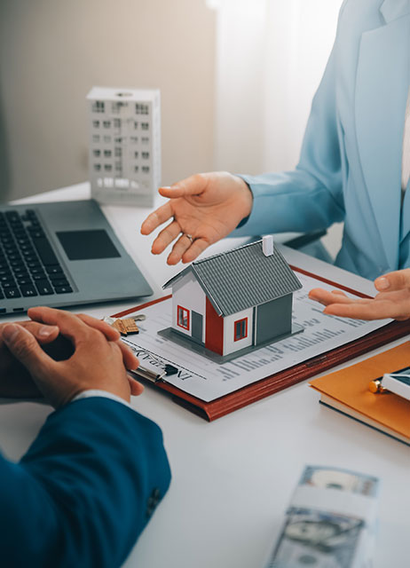 agente inmobiliario explicando contrato a cliente con modelo de casa